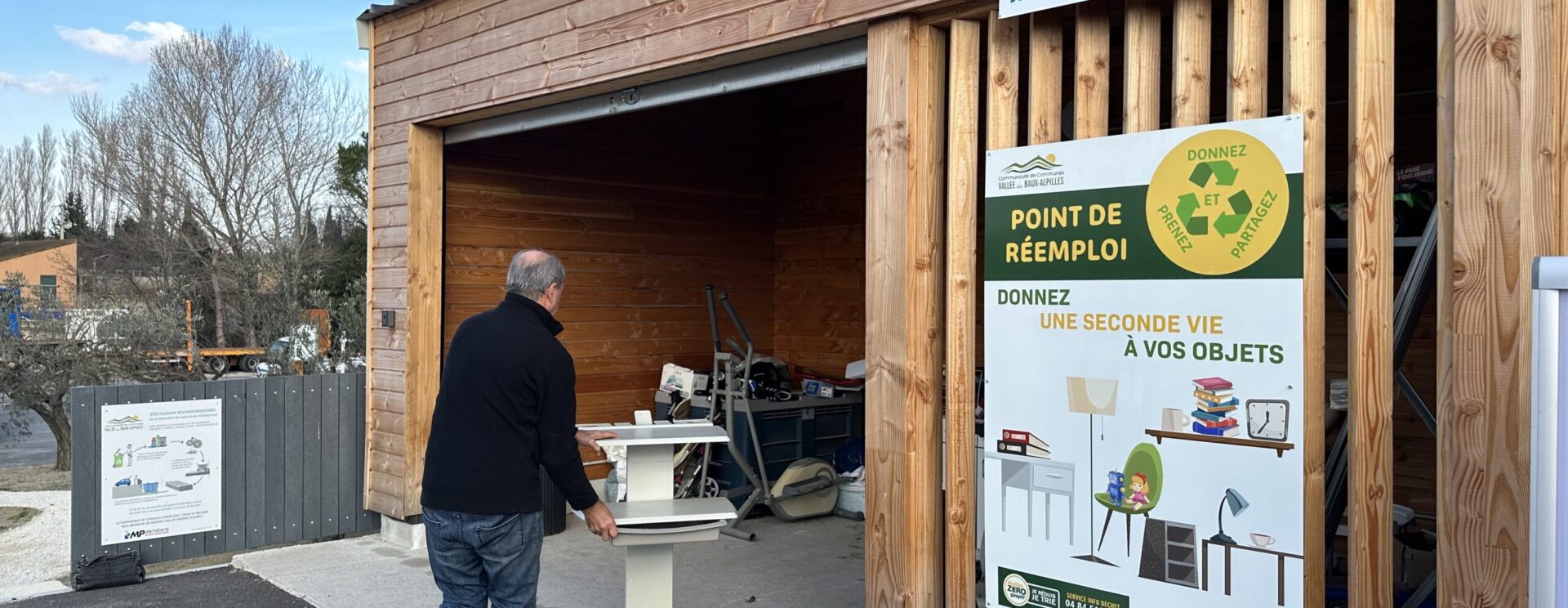 Local de la zone de réemploi à la déchèterie de Maussane avec un monsieur qui y dépose un meuble