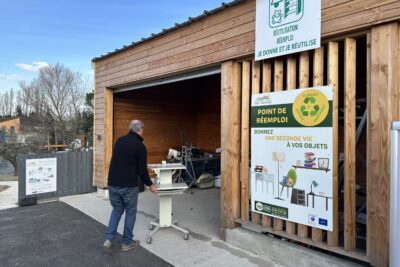 Local de la zone de réemploi à la déchèterie de Maussane avec un monsieur qui y dépose un meuble - Agrandir l'image 1 sur 2, fenêtre modale