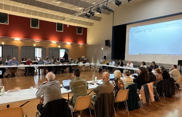 Elus communautaires rassemblés, assis en cercle devant un écran géant qui projettent les documents relatifs au conseil communautaire - Agrandir l'image, fenêtre modale