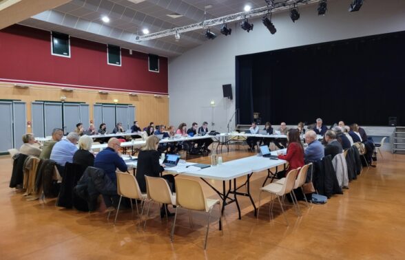 Dans la salle des fêtes, les élus communautaires sont assis en cercle autour des tables afin de voter les délibérations - Agrandir l'image, fenêtre modale